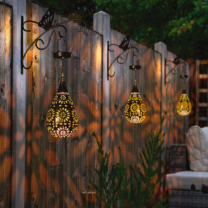 Détail d'une lampe solaire goutte d'eau allumée, offrant une lumière d'ambiance douce pour le jardin extérieur.