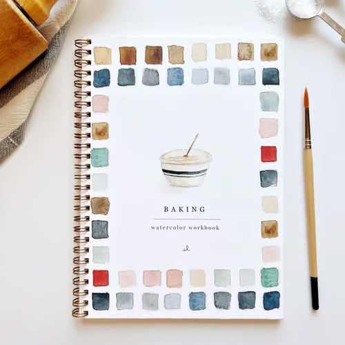 Cahier d'aquarelle posé avec pinceaux et couleurs, un kit peinture parfait pour les fournitures d'art.