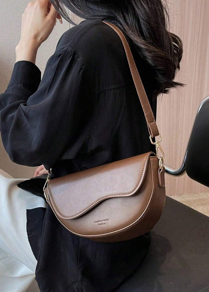 Accessoire femme: sac à main demi-lune minimaliste, style moderne en cuir synthétique de qualité.