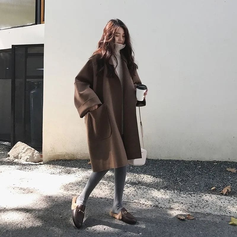 Manteau femme noir chic, coupe longue oversize, double boutonnage, ceinture. Tendance mode élégante.