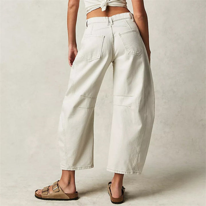 Femme souriante en pantalon large denim, look printanier décontracté et confortable.