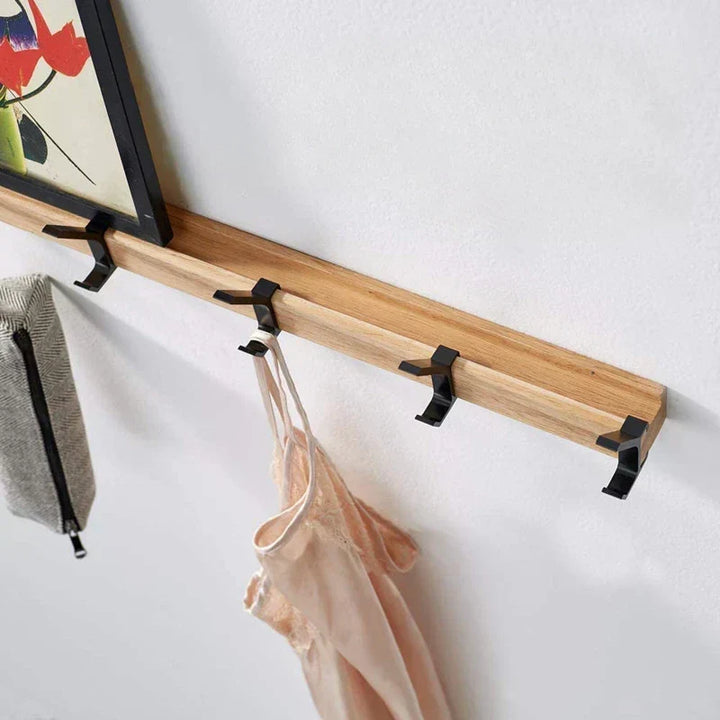 Rangement mural élégant en bois clair et métal noir, patère avec crochets mobiles pour organiser vestes et sacs.