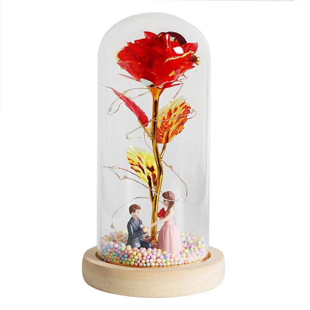 Cloche en verre abritant une rose éternelle et des lumières LED, élégance intemporelle.