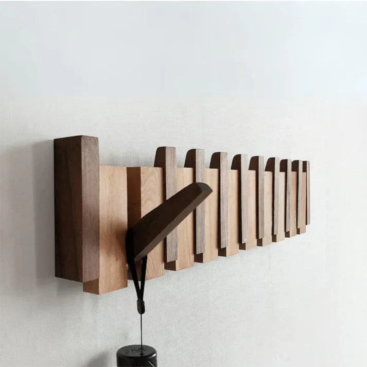 Patère murale pliante en forme de clavier piano. Rangement mural astucieux pour optimiser l'espace dans une petite entrée.