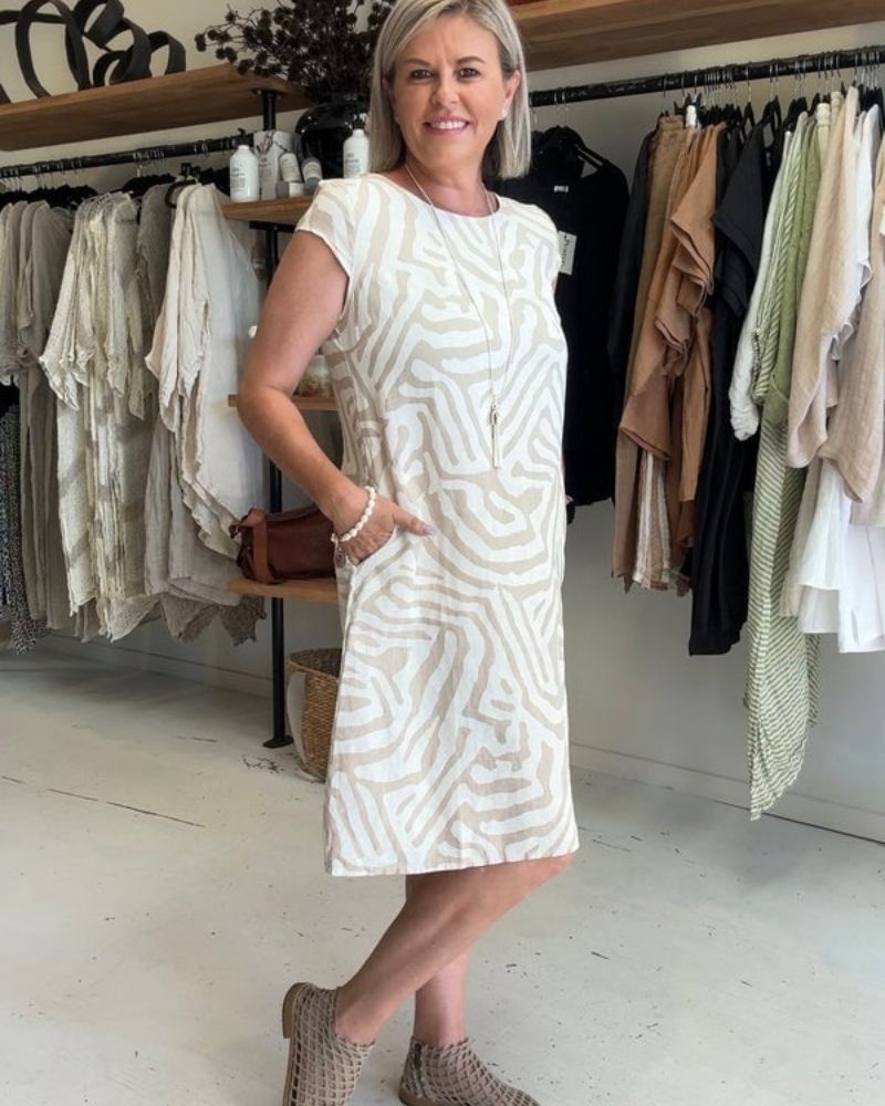 Femme portant une robe midi fluide et décontractée à col rond. Tenue estivale confortable et chic pour les vacances.