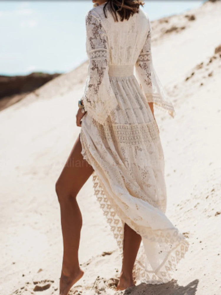 Robe longue blanche ajourée et fluide, col V, manches longues. Parfaite pour soirée, plage ou tenue de jour élégante.