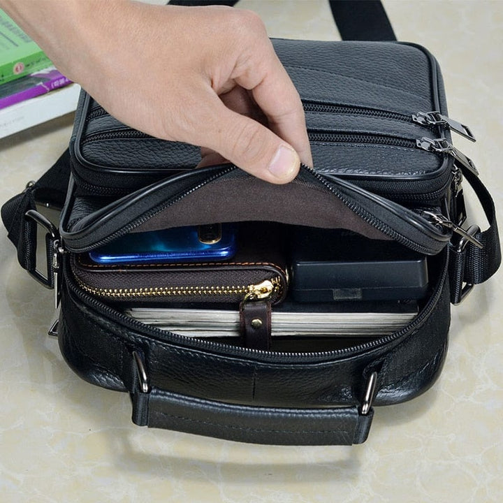 Homme portant un sac bandoulière en cuir véritable. Accroche le sac par la bandoulière sur son épaule.