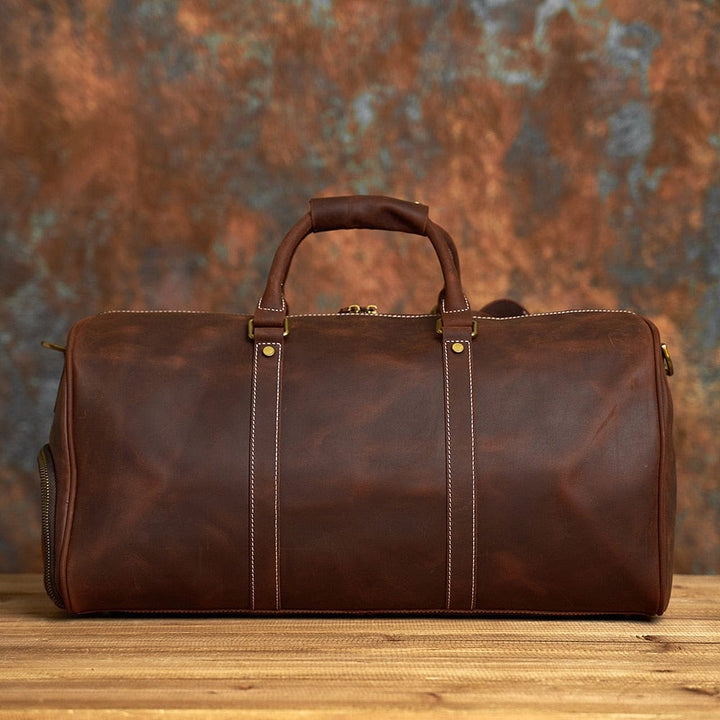 Gros plan sur la texture du cuir crazy horse patiné d'un sac de voyage homme élégant.