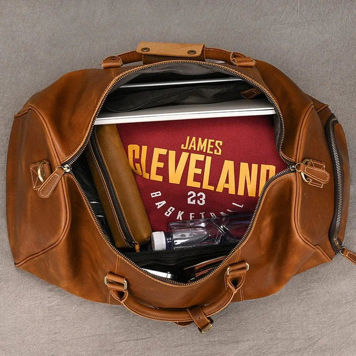 Sac de voyage homme en cuir marron, avec compartiment chaussures séparé pour l'organisation.