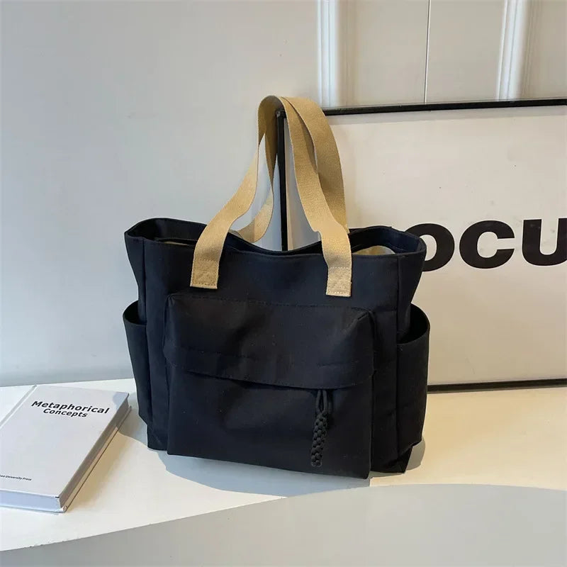 Vue de côté du sac de cours en toile, démontrant sa capacité et sa structure pour les affaires scolaires.