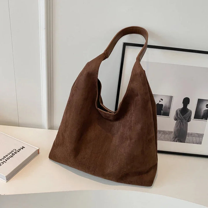 Sac besace femme chic en daim noir, accessoire versatile, complétant parfaitement un look élégant et décontracté.