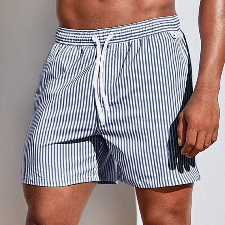 Vue détaillée d'un short de bain homme rayé (blanc/bleu), séchage rapide, pour un look sportif à la piscine.