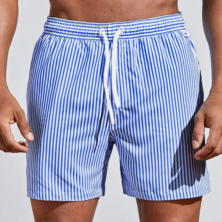 Homme portant un short de bain rayé pour la plage, confort optimal, maillot de bain séchage rapide pour l'été.