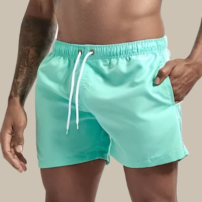 Modèle homme portant un short de bain sur la plage, confort et style assurés pour l'été.