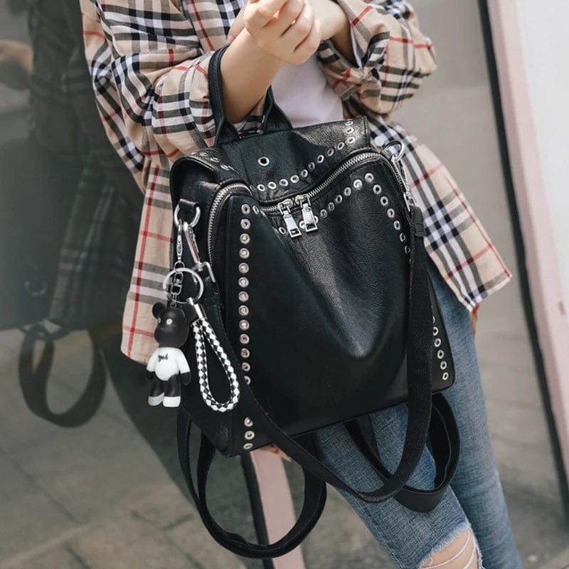 Mini sac à dos convertible en cuir noir porté par une femme, détails en métal doré, look urbain.