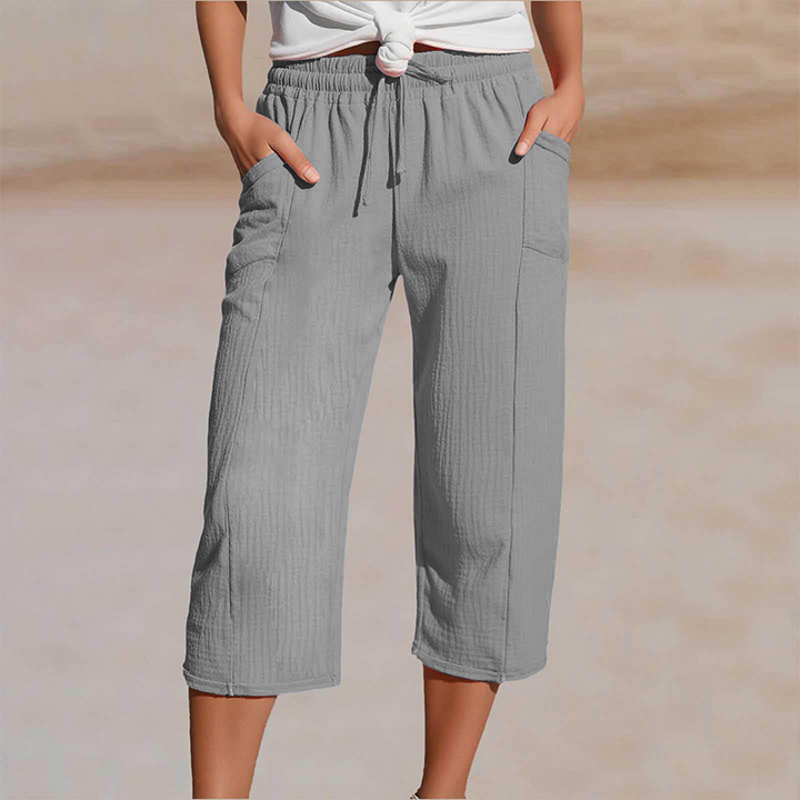 Femme portant un pantalon cropped taille élastique en coton lin, parfait pour l'été.