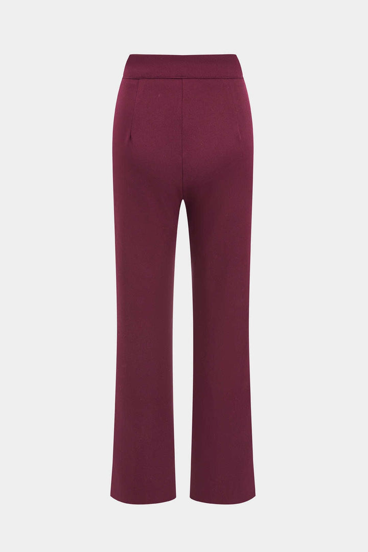 Femme élégante en costume deux pièces rouge : blazer ceinturé et pantalon droit, mode chic et moderne.