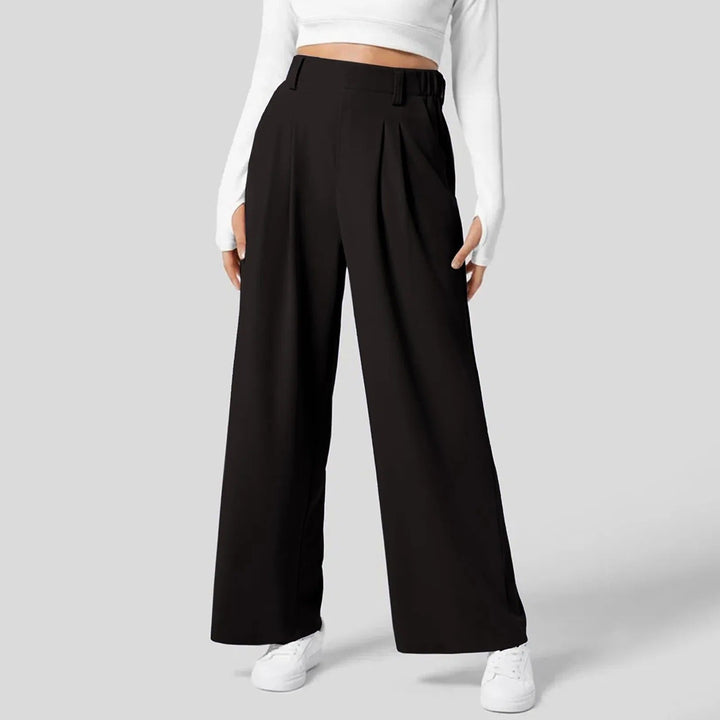 Modèle portant un pantalon large fluide rose clair taille haute. Confortable et chic, pour une silhouette élégante.