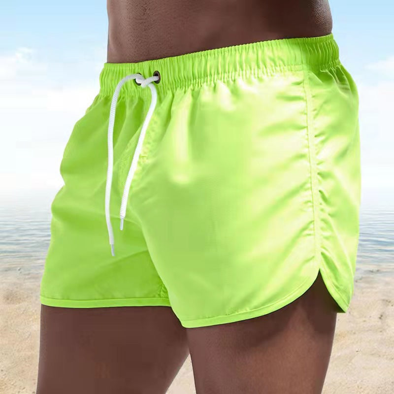 Homme portant un short de bain uni Caspian sur la plage, idéal pour nager et profiter du soleil en été.
