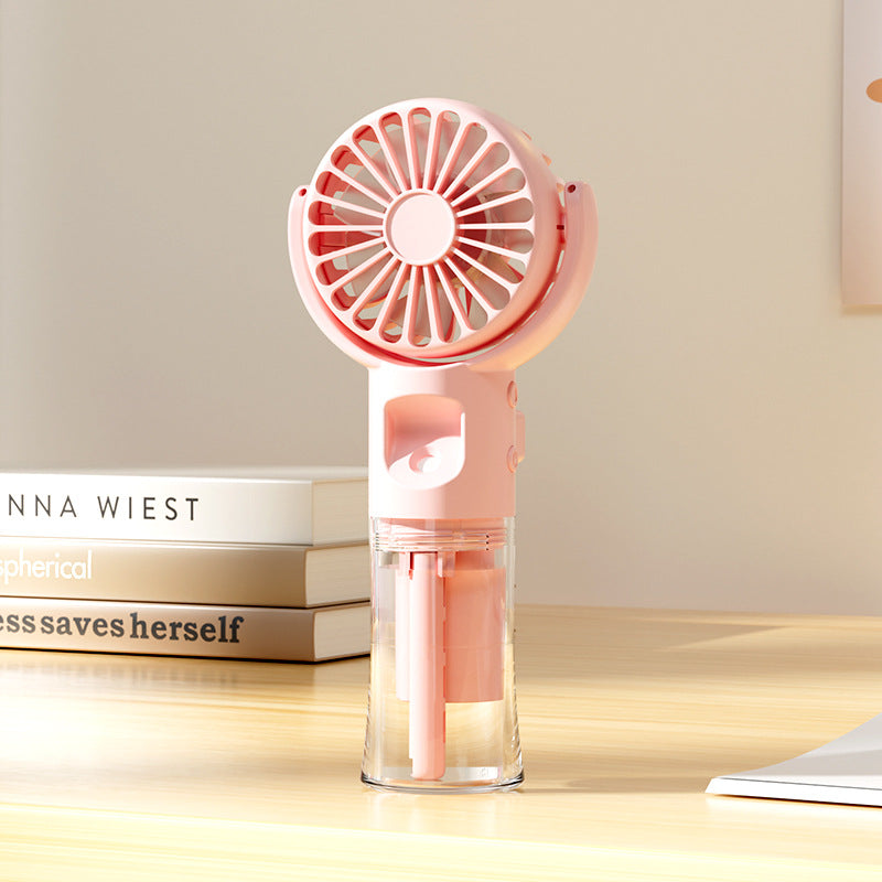 Ventilateur portable brumisateur rose compact pour femme, offrant une fraîcheur instantanée et silencieuse en été.