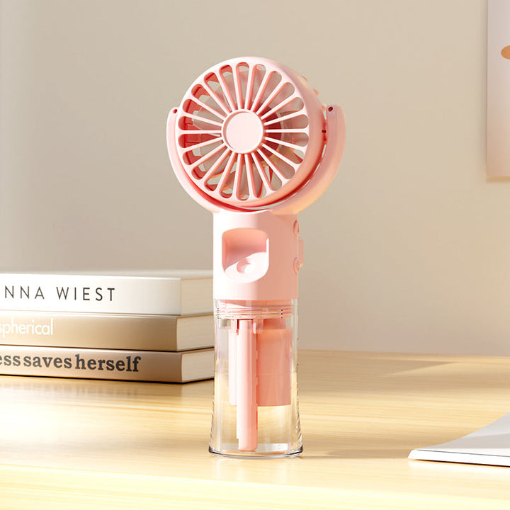 Ventilateur portable brumisateur rose compact pour femme, offrant une fraîcheur instantanée et silencieuse en été.